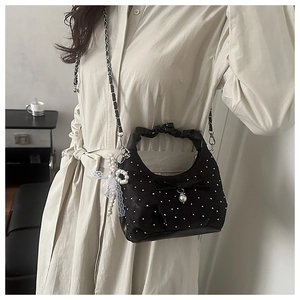Close-up of black polka dot pleated bag with bow detail and pearl charm accents