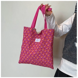 Close-up of floral tote bag with orange patterns, pink straps, and white logo patch