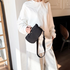 Crossbody wear display of a compact black nylon water bottle bag with wide strap