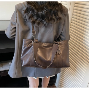 Rear view of a model wearing a soft dark brown vintage faux leather tote bag