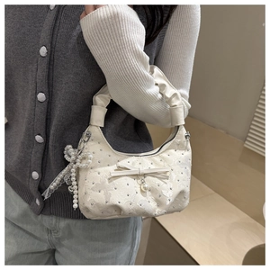 Detail of cream jacquard bag with diamond bow, pearl pendants and pleated handle strap