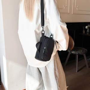 Detail of a minimalist black canvas crossbody bag with adjustable wide fabric strap