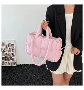 Detail of pink quilted down puffer bag showing side drawstring and soft padded texture