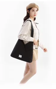 Dettaglio della borsa tote geometrica nera con etichetta tessuta e texture in nylon
