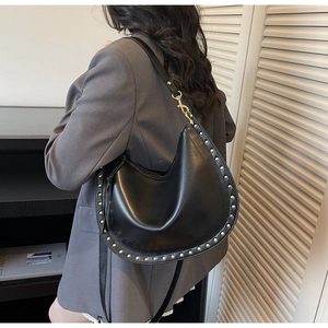 Detail showing a black rivet-studded hobo shoulder bag worn on a model's shoulder