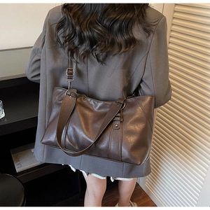 Detail view of large dark brown leather tote bag with adjustable shoulder strap and glossy finish