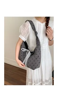 Detail of grey polka dot canvas tote bag featuring a white lace bow and knotted strap