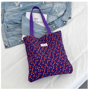Detailed shot of purple floral tote bag with geometric print and white woven label
