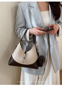Detail view of contrast leather dumpling bag with silver metal buckle on a model