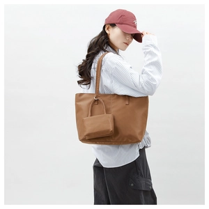 Détail d'un grand sac cabas marron en nylon avec une petite pochette assortie et anneau métal
