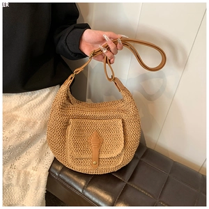 Detail of hand-woven straw shoulder bag featuring a brown leather buckle pocket and strap