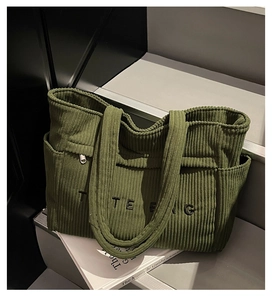 Détail du sac cabas en velours côtelé vert foncé avec poche brodée et texture de haute qualité