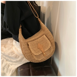 Close-up of khaki straw crescent bag with a leather flap pocket and metal buckle detail
