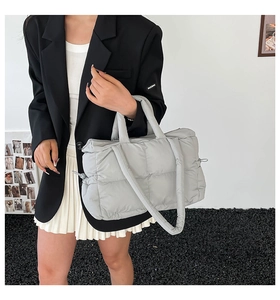 Detail of light grey quilted puffer tote bag featuring classic square stitch and shoulder strap