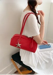 Detail of red leather Boston bag with star pendant and sleek crossbody strap
