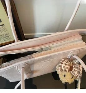 Dettaglio della borsa tote rosa testurizzata con cerniera e ciondolo a forma di orsetto