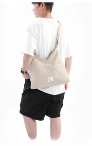 Vista dettagliata di una borsa tote beige con pannelli triangolari indossata da modella