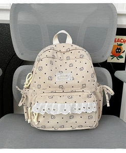 Detail of beige corduroy backpack featuring black dots, bear prints and white lace trim