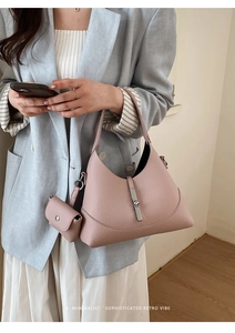 Macro view of silver piston lock and lychee texture on grey-pink leather bag