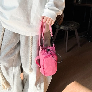 Detail of rose pink nylon drawstring crossbody bag with front zipper pocket