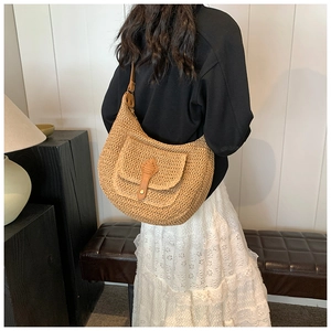 Detail of woven straw shoulder bag with brown leather buckle in minimalist interior setting