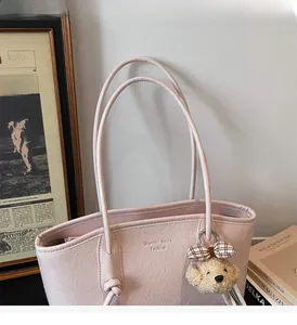 Dettaglio della borsa tote rosa testurizzata con un grazioso ciondolo a forma di orsetto