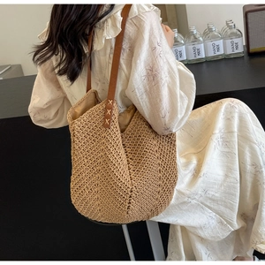 Detailed close-up of woven tote bag with brown leather strap and V-shaped knit texture