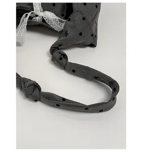 Detail of grey polka dot wide strap with white lace trim and decorative knot