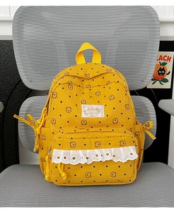 Close-up of yellow corduroy backpack featuring bear patterns and white lace trim detail