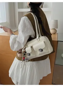 Detail showing the white glossy leather finish and two front pockets with silver buckles