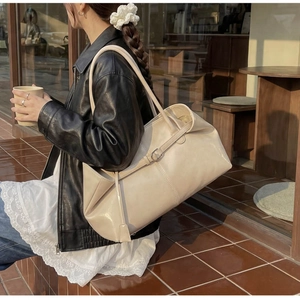 Détail du sac cabas crème avec texture en cuir fin et sangle décorative sur un sac à bandoulière