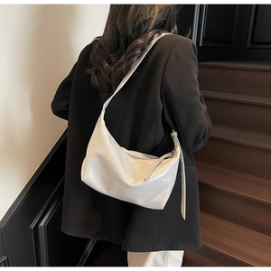 Detail showing the glossy beige hobo bag texture and wide strap on a shoulder