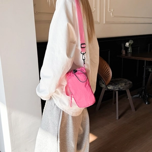 Detail of rose pink nylon crossbody bag with adjustable strap and functional zipper pocket