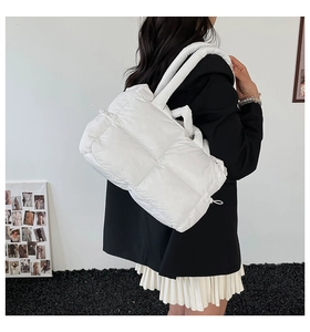 Detail of white quilted down tote bag with padded grid texture and wide handle straps