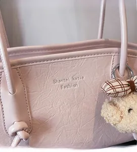 Dettaglio della borsa tote in pelle rosa con trama a grana fine e ciondolo a orsetto