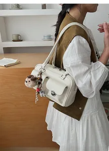 Detail of white minimalist handbag with metal twist lock and cute plush dog charm