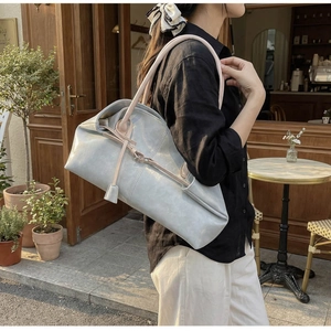 Sac cabas chic en cuir bleu clair avec anses roses présenté dans un café en plein air