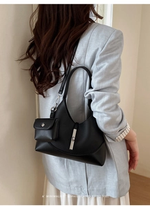 Macro detail of black bucket bag with detachable mini purse and metallic buckle fastener