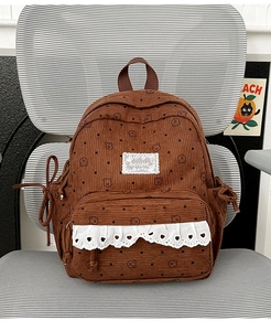Close-up of brown corduroy backpack with cute bear prints and white lace heart detail