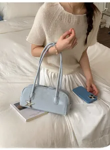 Close-up of light blue leather bowling handbag with silver star charm and zipper detail