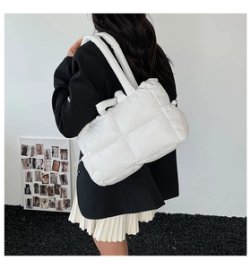 White puffy quilted tote bag with wide handles shown on model for a casual look