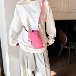 Detail view of pink lightweight crossbody bag with adjustable wide fabric strap on a model