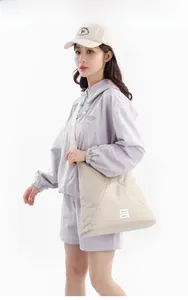 Dettaglio della borsa tote beige con cuciture geometriche e etichetta tessuta bianca