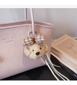 Dettaglio del ciondolo a cane soffice con fiocco a quadri su borsa in pelle rosa