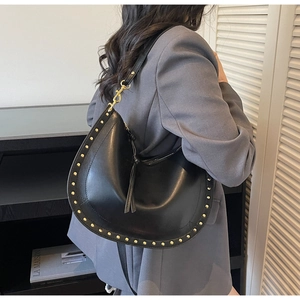 Detail of black leather hobo bag with golden rivets and stylish fringe zipper pulls