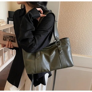 Olive green matte leather tote bag shown on shoulder with silver ring buckles and rivets