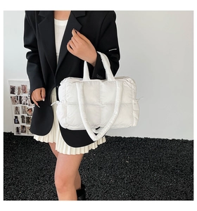 Detail of white quilted puffer tote bag featuring large padded grid pattern and dual straps