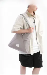 Dettaglio della borsa tote grigia con cuciture geometriche e toppa in tessuto bianco