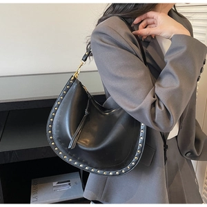 Detailed macro view of black hobo bag with golden studs and fringe zipper decoration