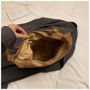 Detail view showing inner fabric lining and zipper closure of woven straw shoulder bag